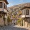 AI-generated illustration of pale timber-framed houses with projecting bays and tiled roofs along a sloping Beypazarı-inspired street.