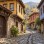 AI-generated illustration of a stone-paved lane and traditional timber-and-stone houses inspired by Cumalıkızık near Bursa.